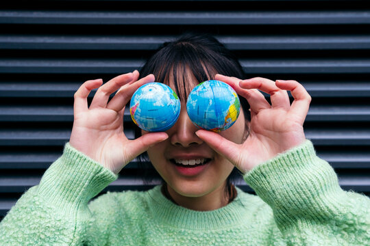 Playful woman covering eyes with toy globes