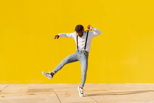 Carefree young man listening music and dancing on footpath