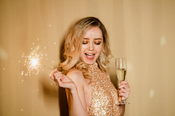 Happy woman with champagne flute holding sparkler at New Year's party