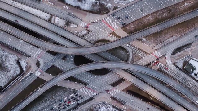 Aerial time lapse traffic jam interchange road, drone shot top down zoom out view roadway intersection in modern city in evening. Timelapse cars driving busy roundabout junction highway in fast motion