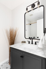 A cozy bathroom with a grey vanity cabinet, hexagon marble tiled floor, and white granite...