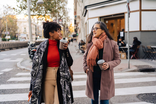 Multiracial ladies with takeaway coffee on city road