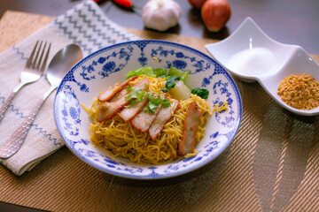 Egg Noodles with Barbeque Pork in Chinese Style Plates on a Wooden Table with Tea and .garnish