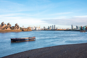 Obraz premium Boat moored on coast with financial district city skyline in background against sky, Boat moored along riverbank