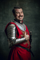 Portrait of smiling man in image of medieval warrior with dirty wounded face wearing equipment...