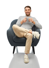 people and furniture concept - happy smiling man with cup of coffee or tea sitting in chair over...