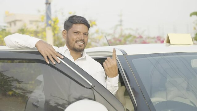 Smiling cab driver showing ink marked finger after voting in election by looking at camera - concept of Indian parliamentary election, democracy and responsibility.