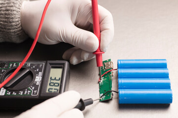 Charge indicator circuit, multimeter red and black poles in the hands of man checking voltage and...