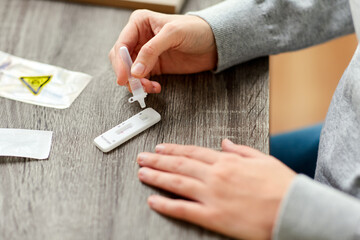 medicine, self testing and pandemic concept - close up of woman making coronavirus test and...