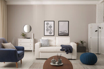Stylish living room interior with white sofa, armchair and beautiful pictures