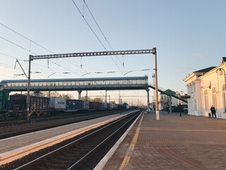 Fototapeta premium The railway station platform. Spring day, sunset. Some people are waiting for their train. 