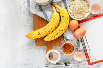 Various ingredients for baking with banana and cinnamon on a gray background. Copy space, top view.