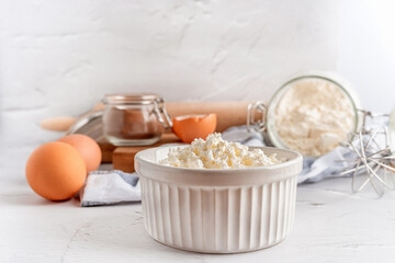 A collection of tools and ingredients for homemade baking with cottage cheese in the foreground. Cooking at home, an appetizing composition of products for cooking