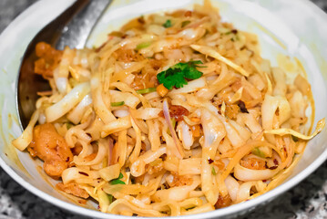 Myanmar traditional or classic white flat noodle salad called Khauk Swe Thoke in white bowl.