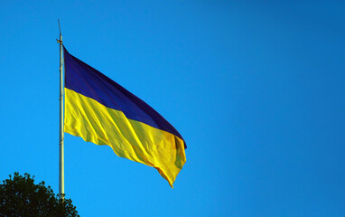 Ukrainian flag against of the clear blue sky background. Copy space.