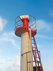 Warning lighthouse in the French West Indies under tropical blue sky. Close up of coastal lighthouse. Reef Lighthouse with bright beautiful blue tropical sky in the background. Maritime signage.