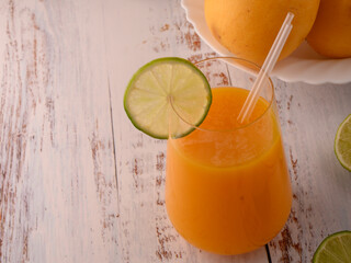 Mango juice closeup with lime slice on white vintage wooden table © ALEKSEI