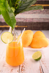 Mango martini and plate of mango and lime. Vase with tropical leaves on left © ALEKSEI