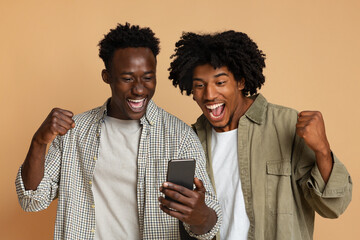 Online Win. Two Excited Black Guys Celebrating Success With Smartphone