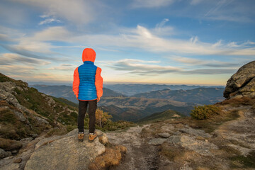 Fototapeta premium Young child boy hiker standing in mountains enjoying view of amazing mountain landscape.