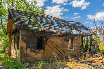 Burnt wooden house on city street. Abandoned destroyed residential building. Consequences of fire, tragedy. Concept of fire careless handling