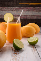 Tangerine juice with lime slice on white vintage wooden desktop with mangos © ALEKSEI