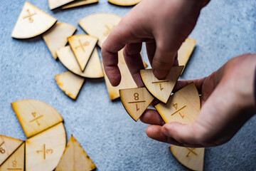 Close-up of a child's hand holding fraction pie chart puzzle pieces