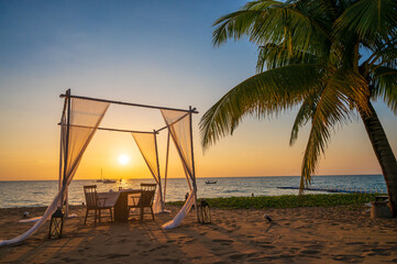 Luxury and romantic dinning place on the beach with palm tree on sunset sky