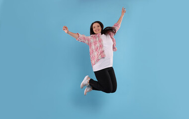 Beautiful overweight woman jumping on turquoise background
