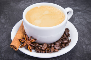 Coffee in white cup and roasted dark coffee beans with seasonings