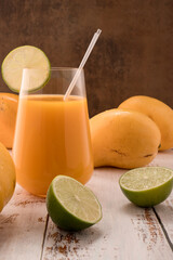 Mandarine drink with lime slice on white vintage wooden desktop with mangos © ALEKSEI