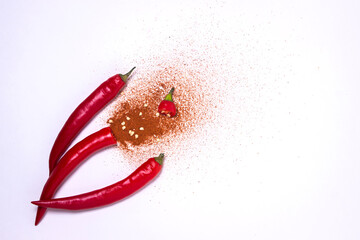 Cut in half red chili peppers with ground red chili peppers on a white background