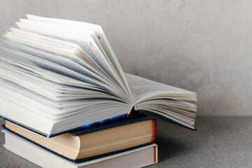 an open book lies on a stack of textbooks, copy space