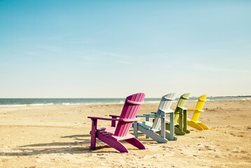 Fototapeta na wymiar Colorful lounge Adirondack chairs at Atlantic ocean beach. North Carolina vacation scene.