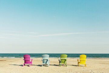 Colorful lounge Adirondack chairs at Atlantic ocean beach. North Carolina vacation scene.
