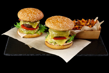two Big burgers and sweet potato isolated on black stone plate. black background. close up