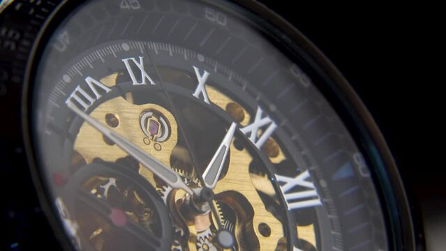 Beautiful mechanical gold watch with open gears and mechanism.The dial of a vintage watch with Roman numerals,watch the time and take your time.Hands of the clock close-up,the passage of time.The past