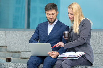 successful businessmen man and woman with documents and laptop in hands discuss business projects