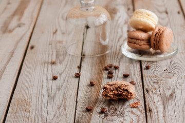 Coffee and vanilla macarons on grey wooden background.
