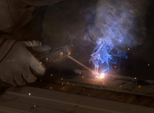 a male welder  sits with an electrode holder in his hand. welding seam concept..