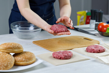 Woman's hand forming a beef meat for a hamburger party. Portioning ground meat. Homemade burgers. Making food at home. close up