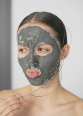 Young beautiful healthy woman's face. Medicine and cosmetology. Doctor's hands in white gloves. Clay for face. Nice lips, long neck. Clear skin. Brown hair. Facial mask. Peeling. Skin and body care