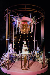 Modern beautiful wedding arch with lots of flowers and a large wedding cake.
