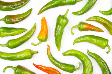green hot peppers evenly spread on a white background. vitamin vegetables for health