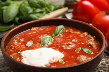 Bowl of delicious stuffed pepper soup on table, closeup