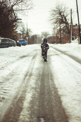 Fototapeta na wymiar man walks forward in the footsteps of a car in winter 