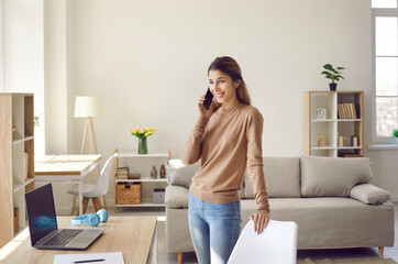 Young female business owner dropshipping at home talking on mobile phone and taking orders....