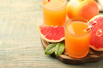 Glasses of delicious grapefruit juice on wooden table, space for text