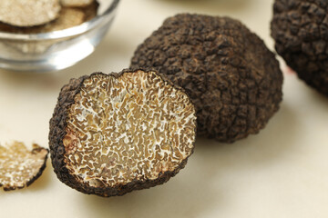 Whole and cut black truffles on light table, closeup