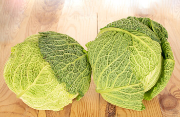 Two bales of juicy Savoy cabbage on a wooden table , macro.